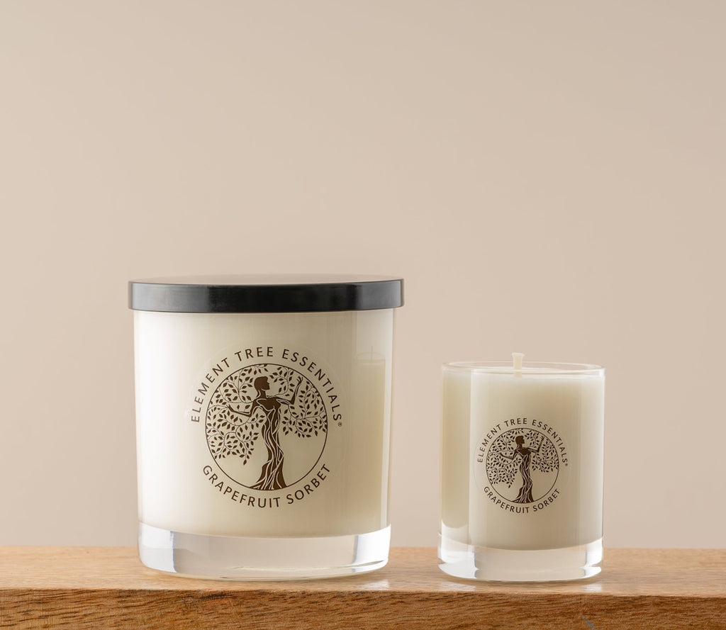 A photo of two different sized lotion candles. They are both Grapefruit Sorbet scent in a clear glass vessel. One is 11 ounce and one is a 3 ounce votive.